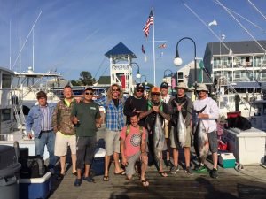 Handful of anglers pose on the dock holding large fish