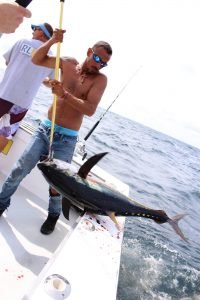 Man bringing a tuna on board a fishing boat